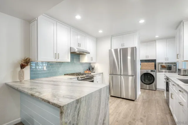 a kitchen with a refrigerator a stove a sink and white cabinets with wooden floor