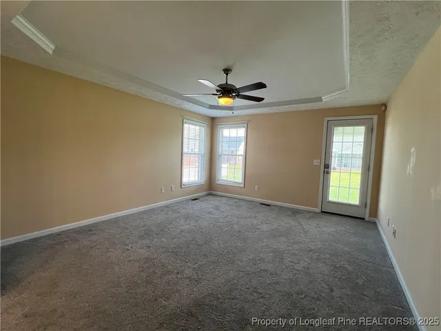 an empty room with windows and fan