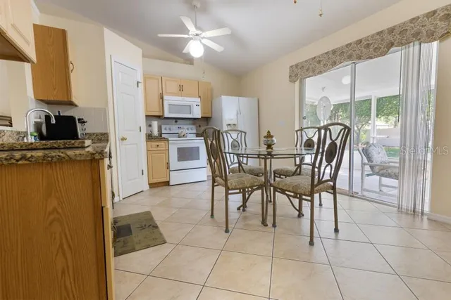 a view of a dining room with furniture a chandelier and kitchen view