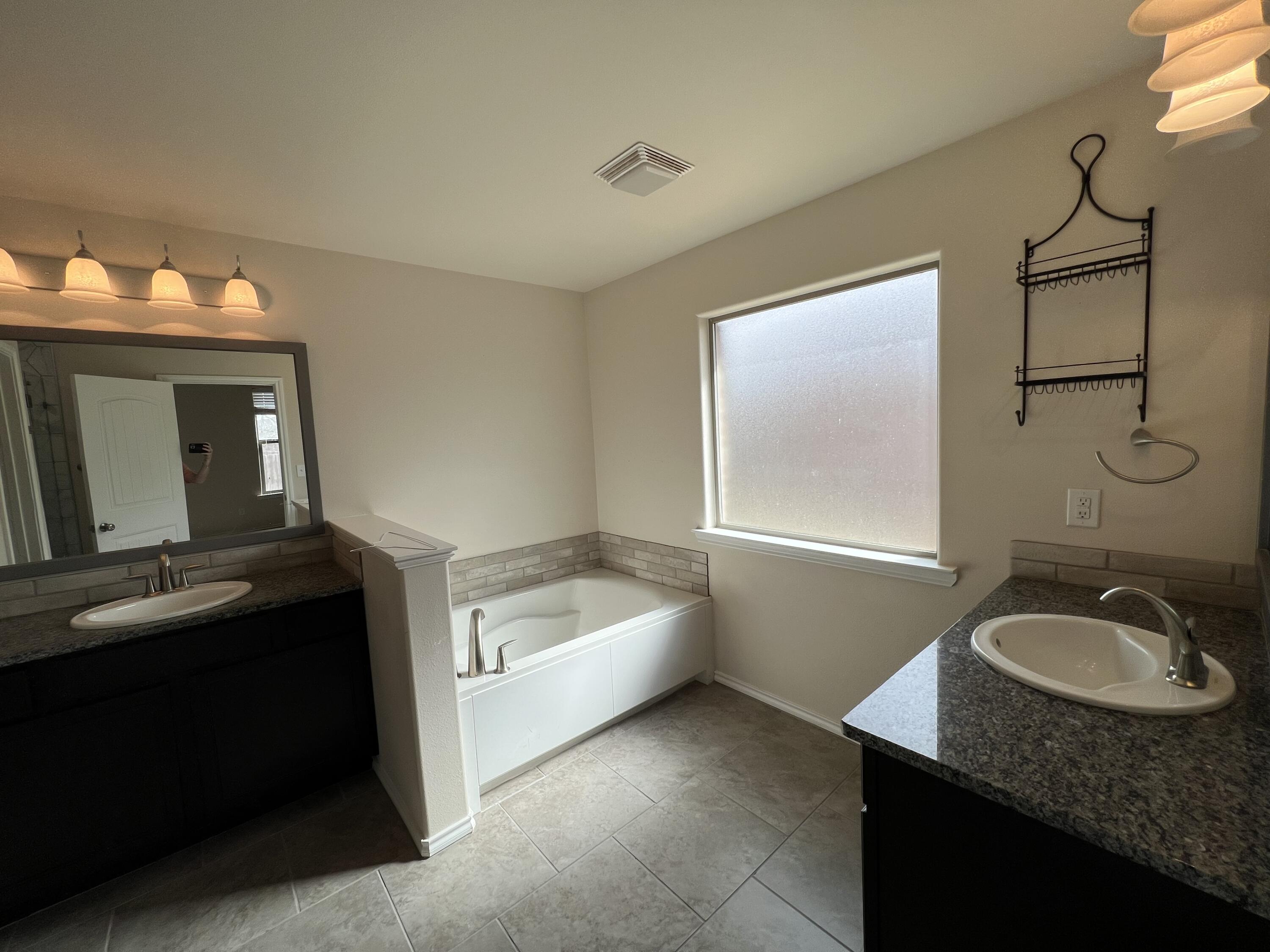 7349 100th Street Lubbock, TX 79424 - Photo 22 of 28 a bathroom with a granite countertop sink and a mirror
