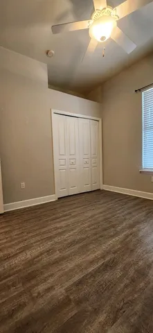 a view of an empty room with wooden floor and windows