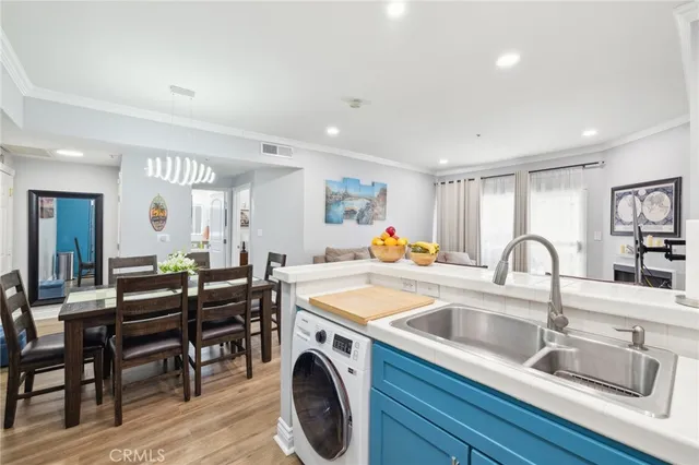 a open kitchen with stainless steel appliances granite countertop a table chairs sink and wooden floor