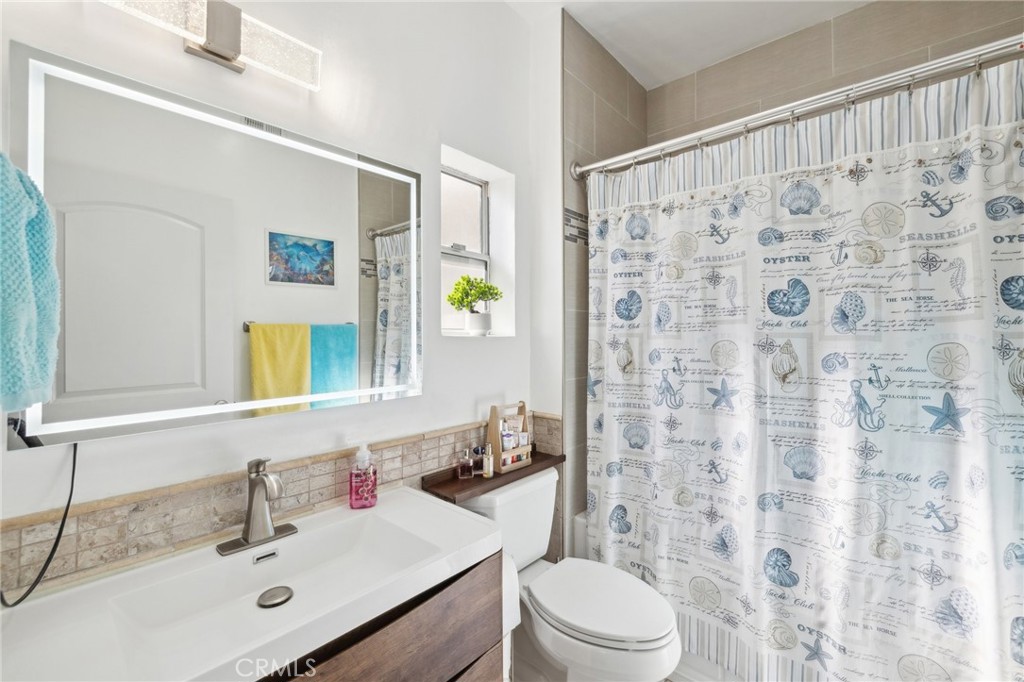 14914 Hamlin Street, Unit 104 Van Nuys, CA 91411 - Photo 7 of 10 a bathroom with a sink toilet a mirror and shower curtain