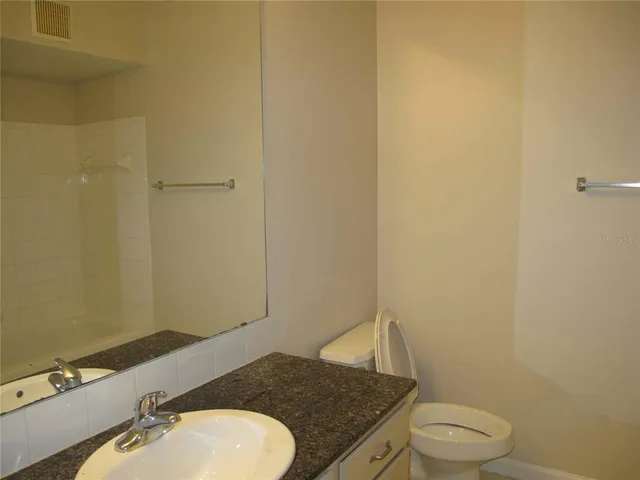 a bathroom with a granite countertop sink toilet and a mirror