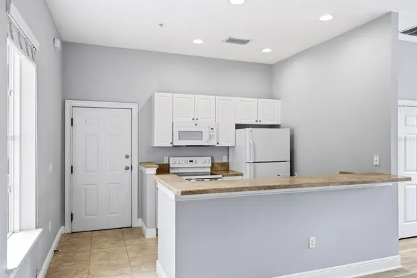 a kitchen with stainless steel appliances granite countertop a refrigerator a sink and white cabinets