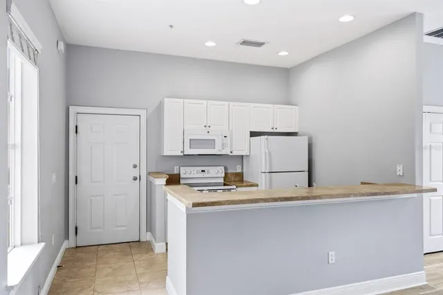 a kitchen with stainless steel appliances granite countertop a refrigerator a sink and white cabinets
