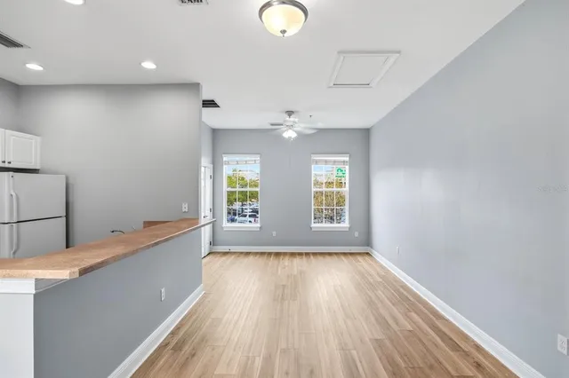 a view of empty room with wooden floor and fan