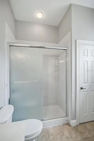a bathroom with a shower a toilet and a glass window