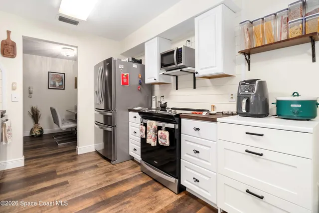 a kitchen with stainless steel appliances cabinets and a wooden floor