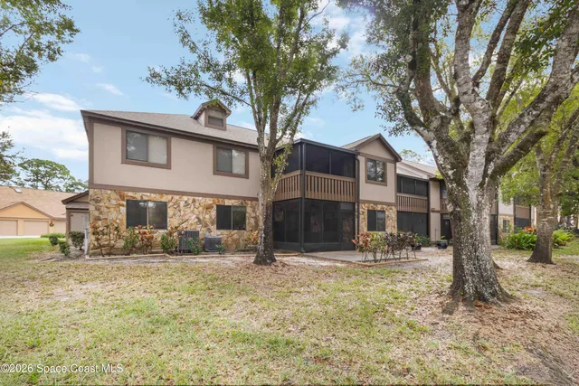 a front view of a house with large trees