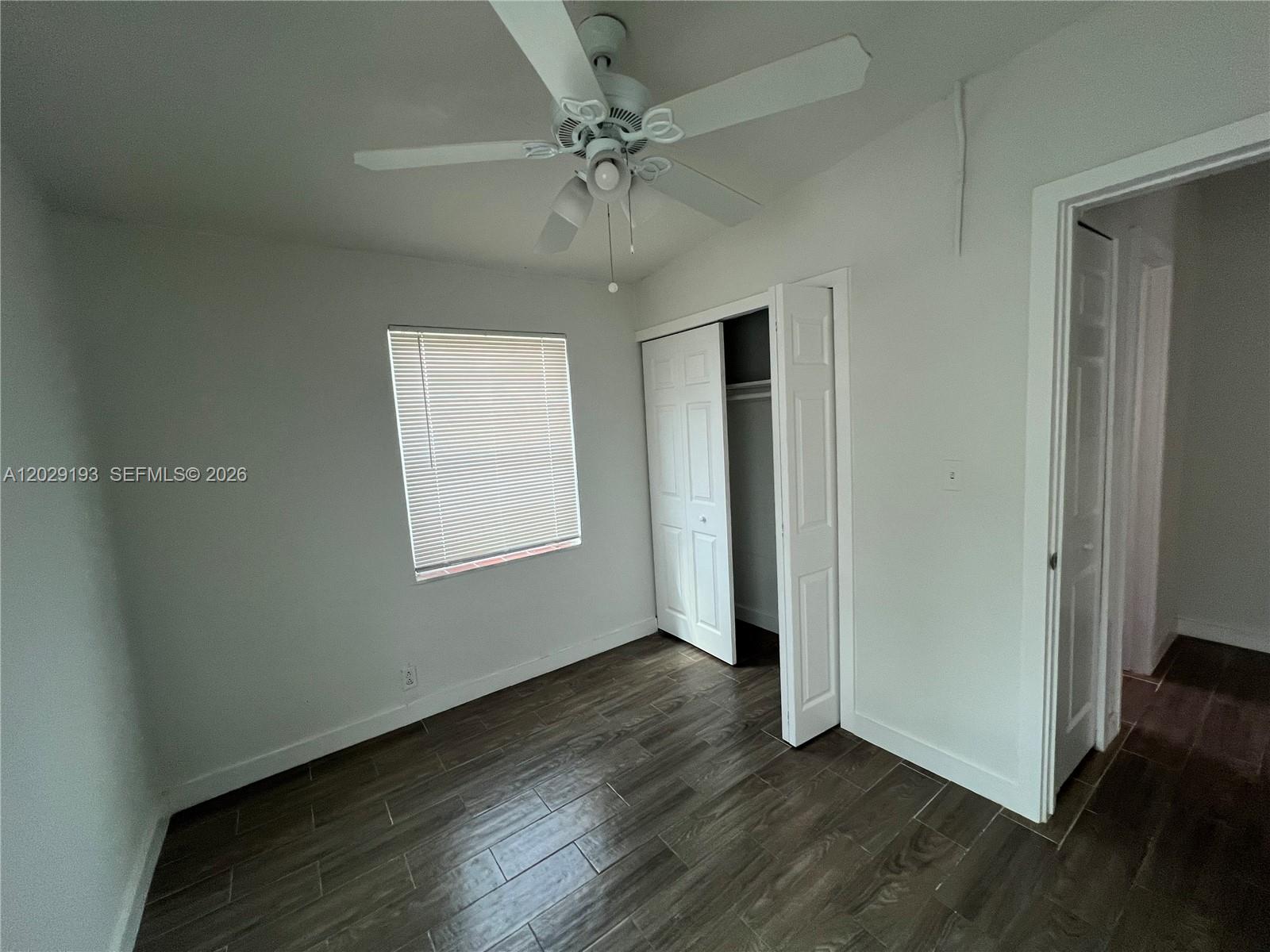 2240 Rutland Street Opa-Locka, FL 33054 - Photo 4 of 11 an empty room with wooden floor chandelier fan and windows