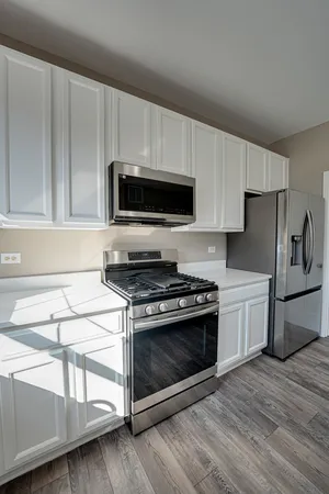 a kitchen with stainless steel appliances a stove a microwave and white cabinets