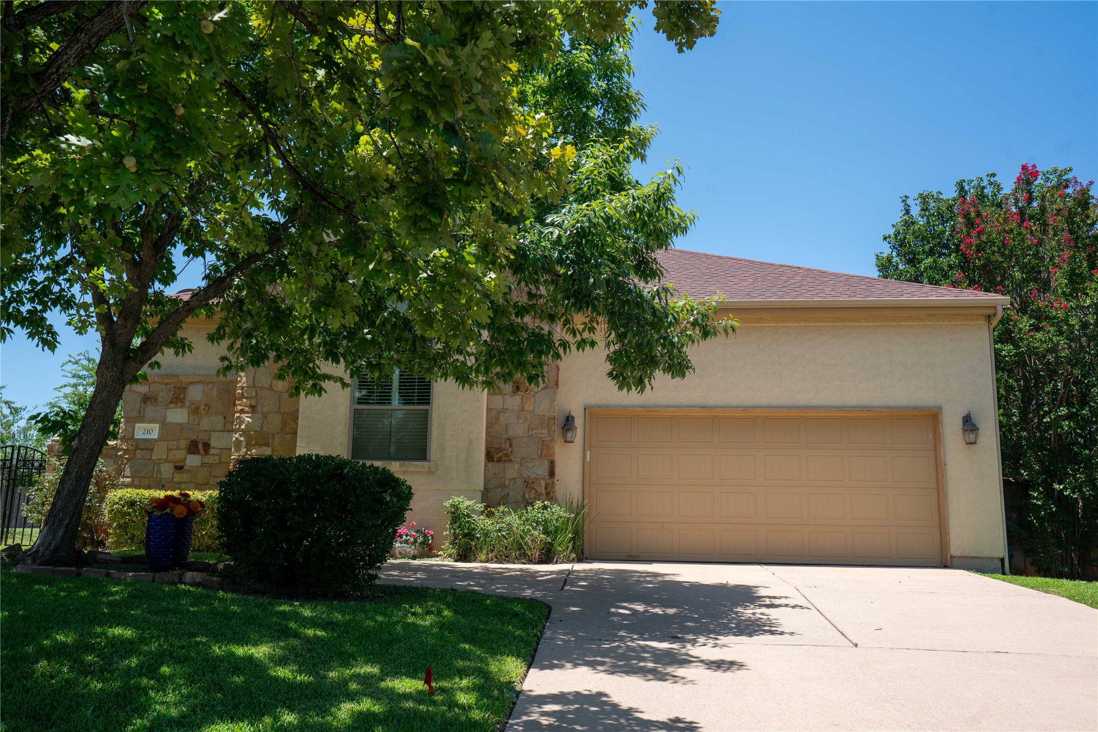 A well-maintained facade features a two-car garage, manicured shrubs, and a welcoming pathway.