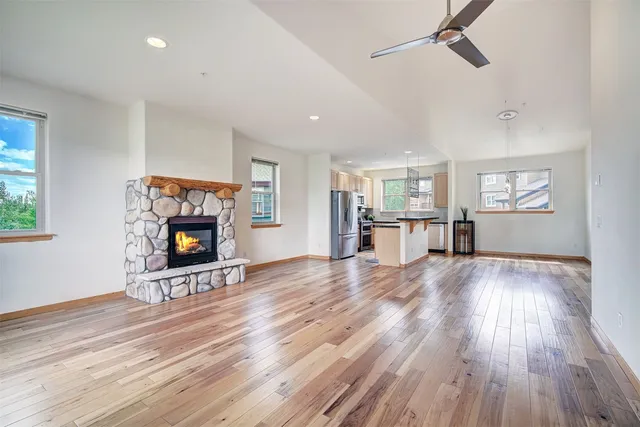 an empty room with wooden floor a fireplace and windows