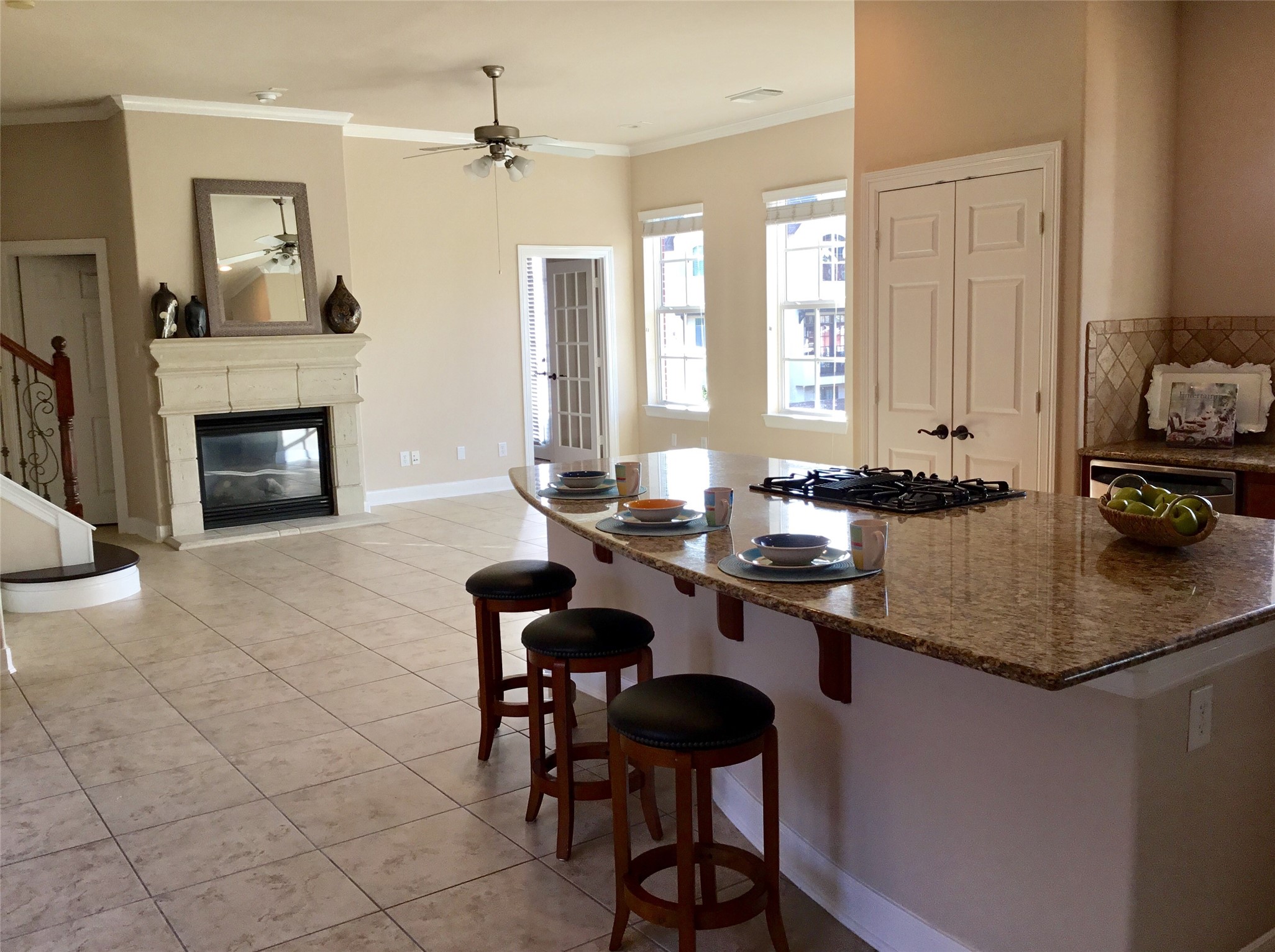 2 Islewood Boulevard Spring, TX 77380 - Photo 11 of 48 The spacious kitchen features a large granite island with seating, a cooktop, and ample natural light. The open layout includes tiled flooring, a cozy fireplace, and easy access to adjacent rooms, creating an inviting and functional space in highly desirable East Shore Community.