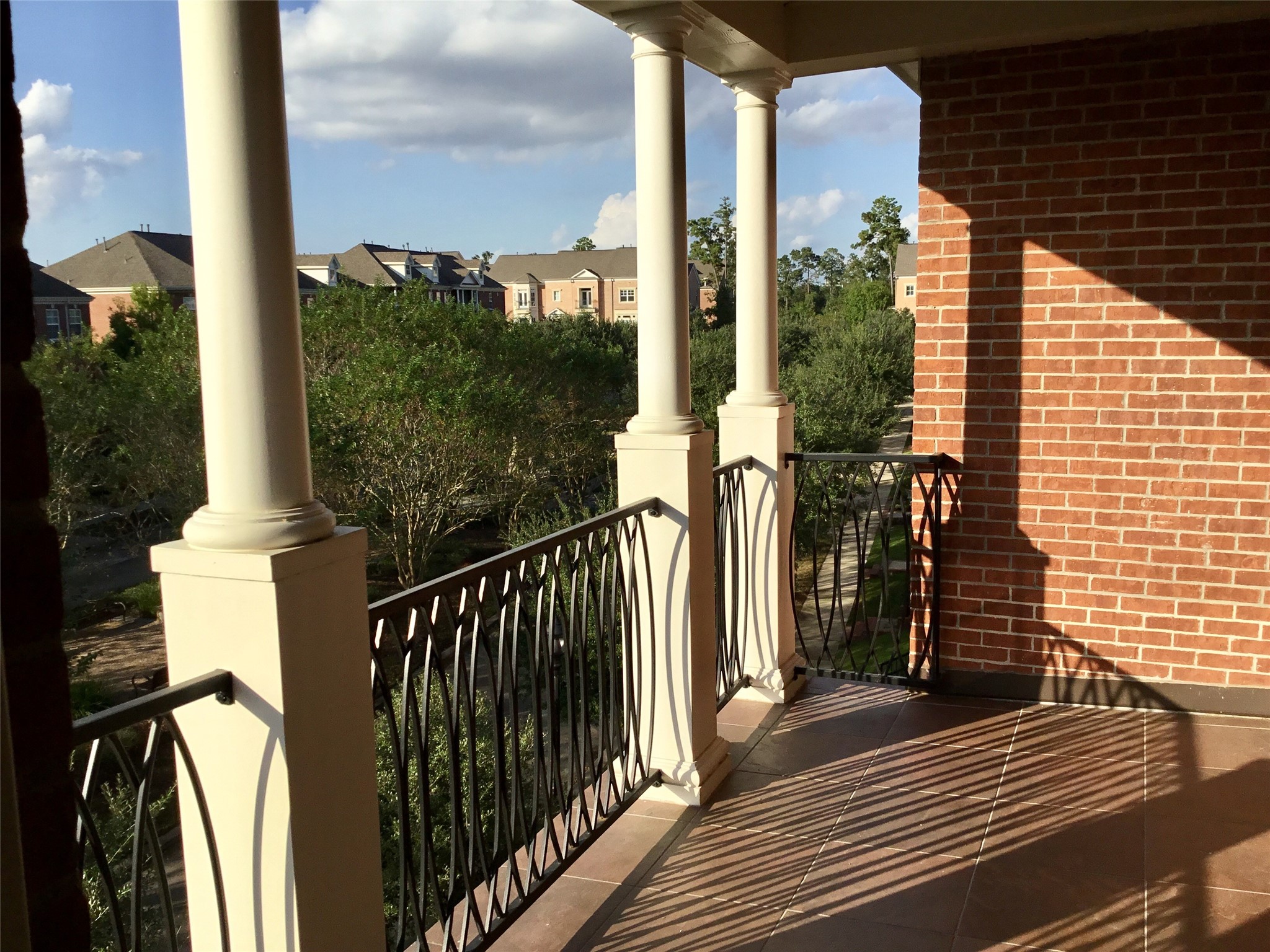 2 Islewood Boulevard Spring, TX 77380 - Photo 28 of 48 This photo showcases a spacious 3rd floor balcony with elegant columns and wrought-iron railings. It offers a scenic view of a lush neighborhood, perfect for relaxing or your morning coffee.