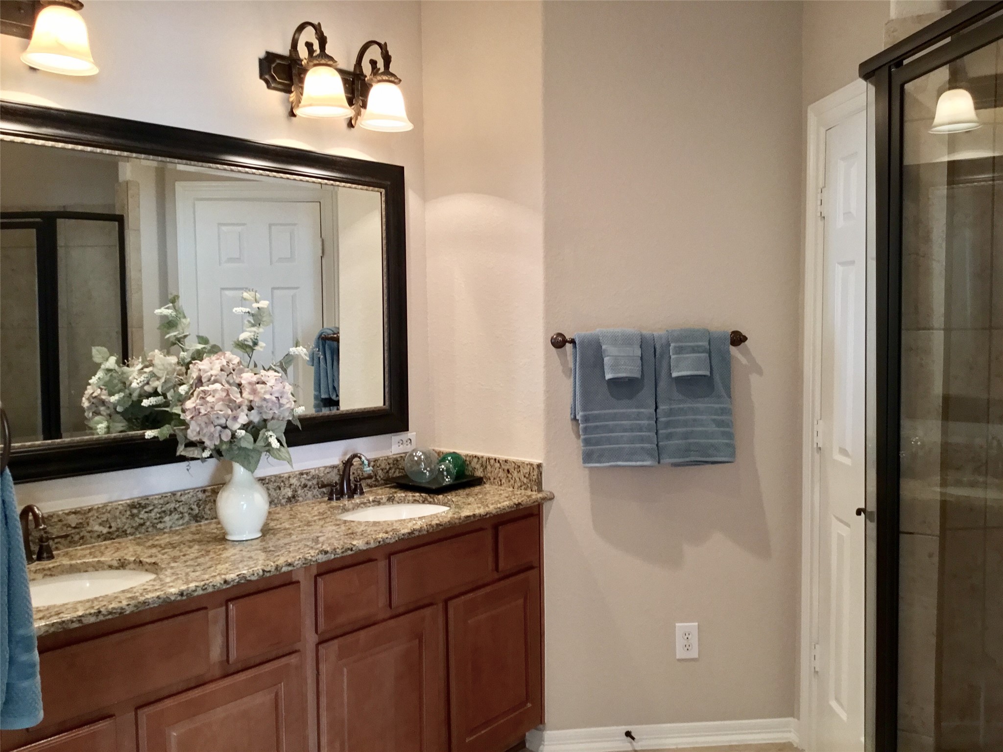 2 Islewood Boulevard Spring, TX 77380 - Photo 29 of 48 The primary bathroom features a double vanity with granite countertops, elegant lighting, and a large mirror. It includes a glass-enclosed shower and a privacy room.