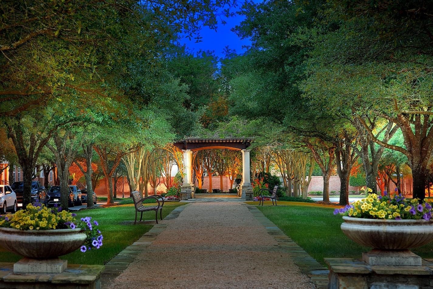 2 Islewood Boulevard Spring, TX 77380 - Photo 38 of 48 This photo showcases a beautifully landscaped garden path with lush trees and vibrant flowers. The pathway leads to a charming pergola, creating a serene and inviting outdoor space perfect for relaxation.