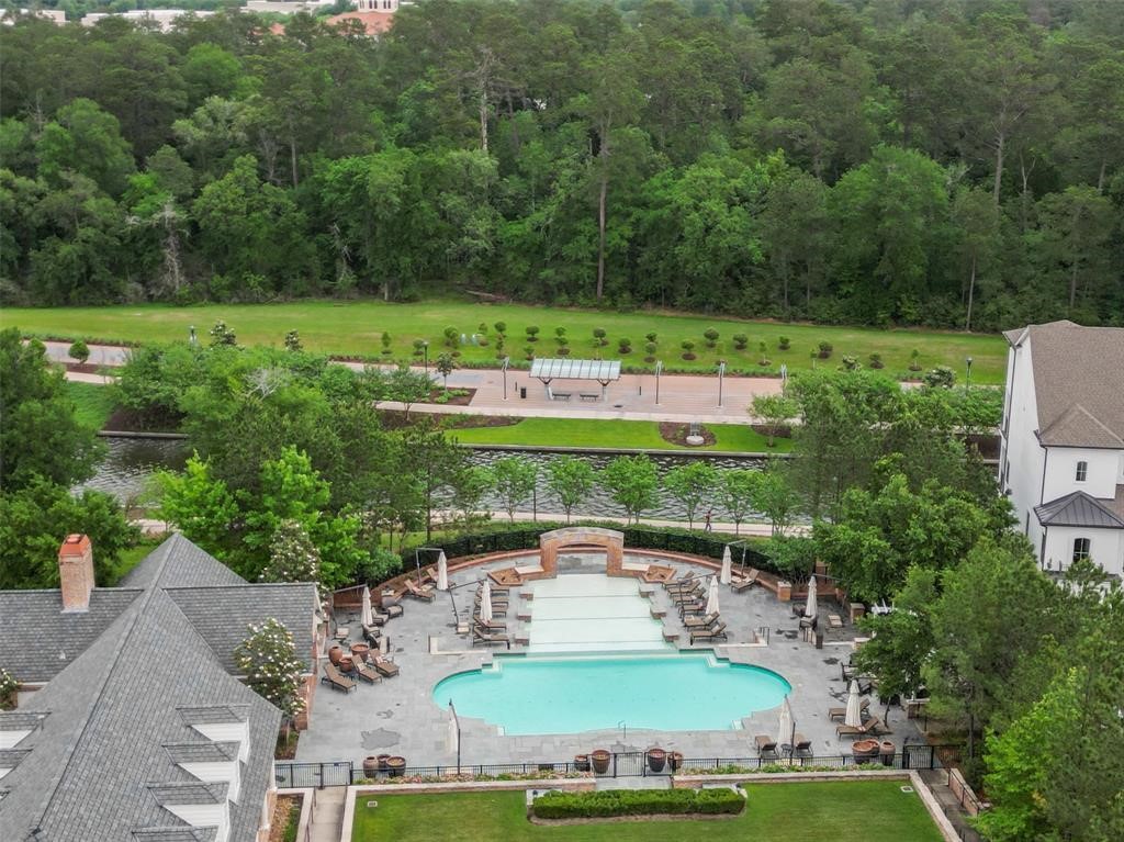 2 Islewood Boulevard Spring, TX 77380 - Photo 45 of 48 A luxurious community center with a stunning multi-level pool, surrounded by elegant patio furniture and umbrellas. The brick architecture of the clubhouse complements the serene, landscaped setting, offering a resort-like ambiance. The Waterway leads to Lake Woodlands and the Trolly Stop is across the way.