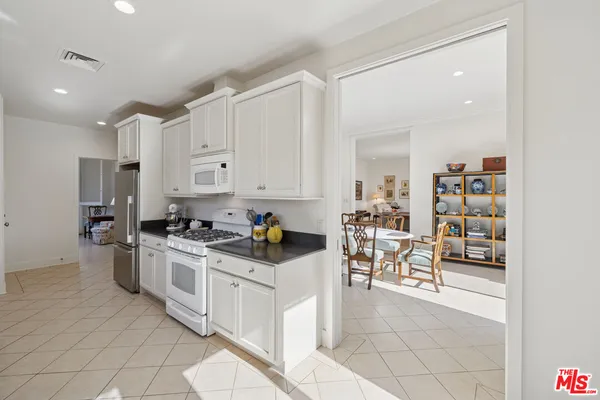a kitchen with white cabinets and appliances