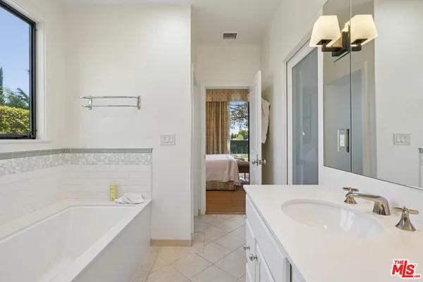 a bathroom with a tub a sink and mirror