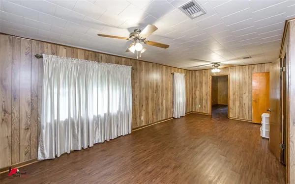 an empty room with wooden floor fan and windows