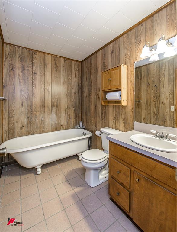 1732 King Orchard Road Sarepta, LA 71071 - Photo 20 of 40 Bathroom with a freestanding tub, tile patterned floors, toilet, vanity, and wood walls