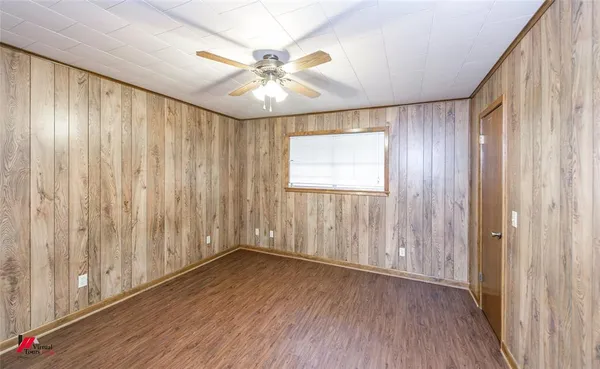 an empty room with wooden floor fan and windows