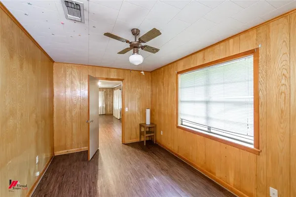 a view of empty room with wooden floor and fan
