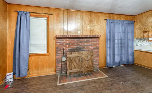 an empty room with wooden floor windows and entryway