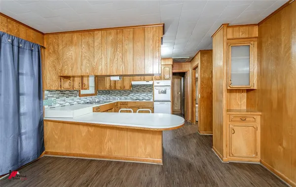 a kitchen with stainless steel appliances granite countertop a refrigerator a sink and wooden floors