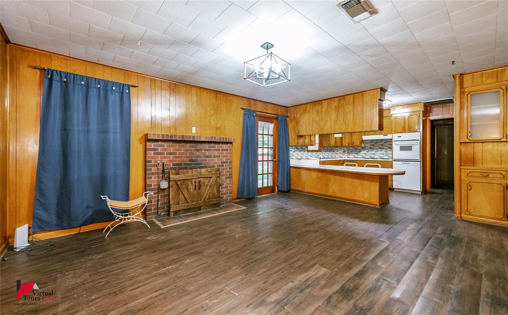 1732 King Orchard Road Sarepta, LA 71071 - Photo 36 of 40 Kitchen with brown cabinets, light countertops, a peninsula, dark wood-type flooring, and wood walls