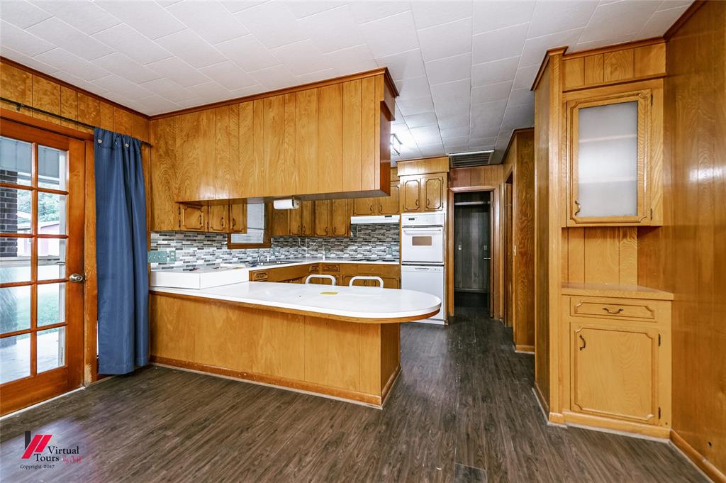 1732 King Orchard Road Sarepta, LA 71071 - Photo 37 of 40 Kitchen with a peninsula, brown cabinets, light countertops, dark wood finished floors, and tasteful backsplash