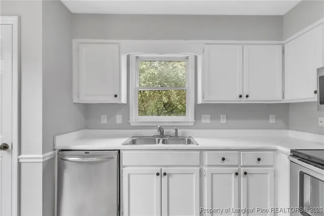 a kitchen with stainless steel appliances granite countertop white cabinets sink and window