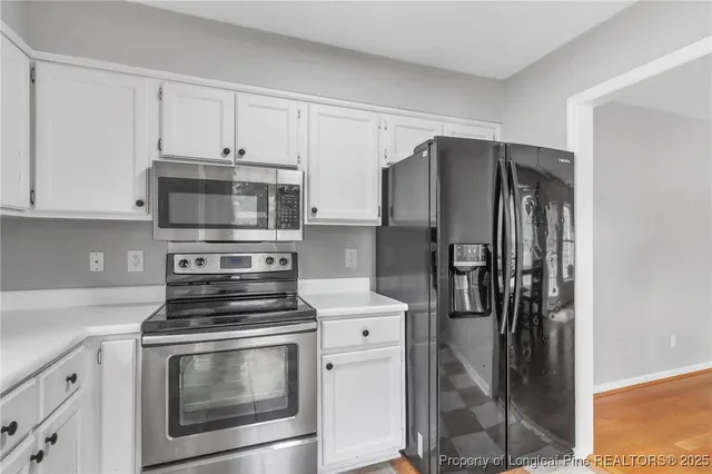 a kitchen with stainless steel appliances white cabinets and a refrigerator