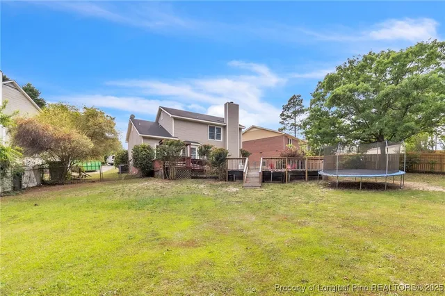 a swimming pool that has lawn chairs and a dining table under an umbrella