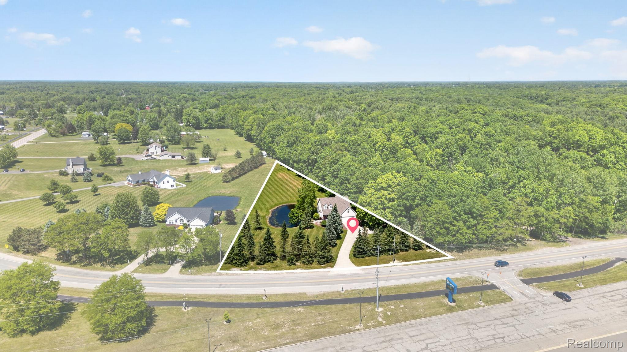 9055 Hegel Road Grand Blanc, MI 48439 - Photo 49 of 62 Aerial perspective showcasing a property featuring a private pond, mature trees, manicured lawn, and a paved driveway leading to a residence