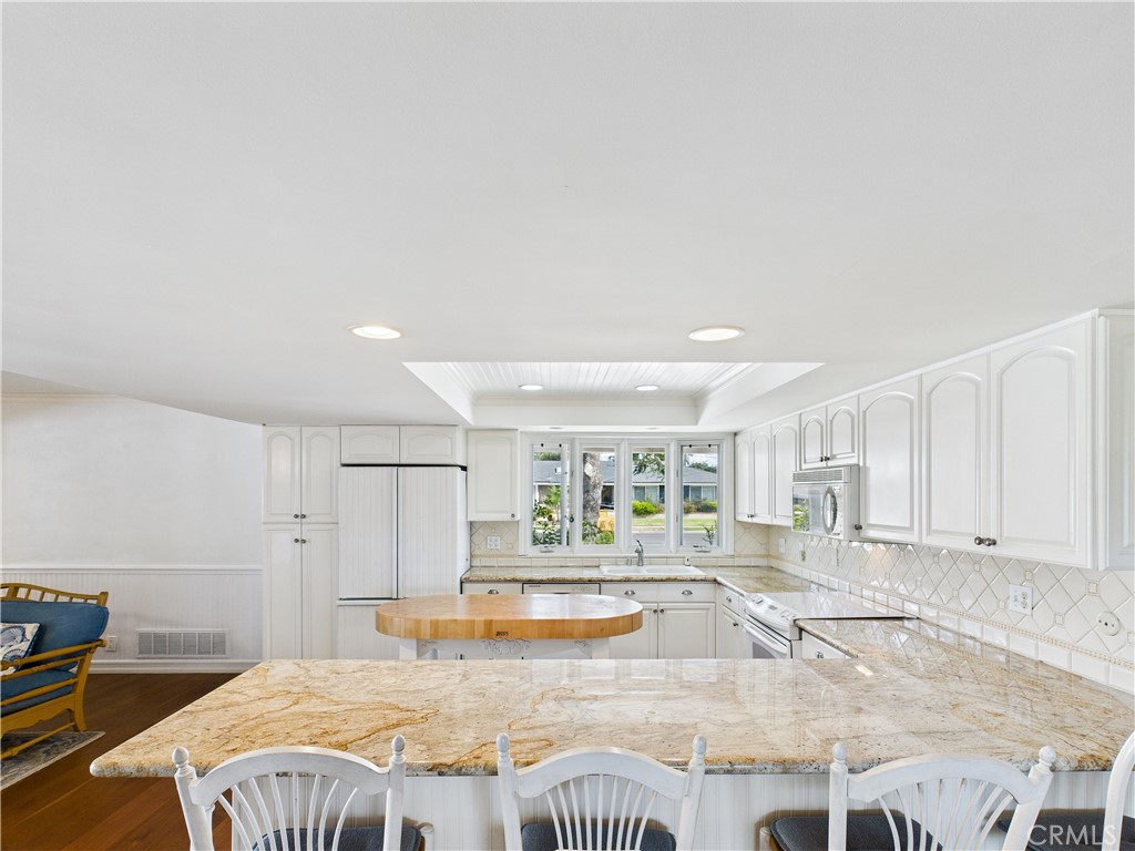 2857 Ellesmere Avenue Costa Mesa, CA 92626 - Photo 11 of 45 a large white kitchen with kitchen island a stove a sink and a counter top space