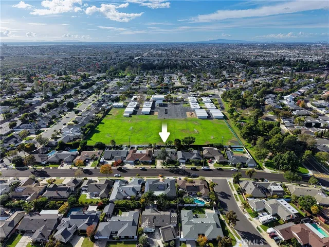 an aerial view of a residential houses with outdoor space and trees