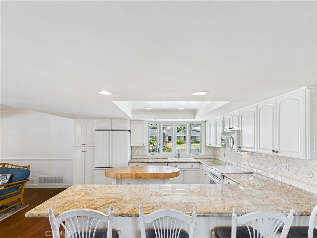 2857 Ellesmere Avenue Costa Mesa, CA 92626 - Photo 4 of 45 a large white kitchen with kitchen island a stove a sink and a counter top space