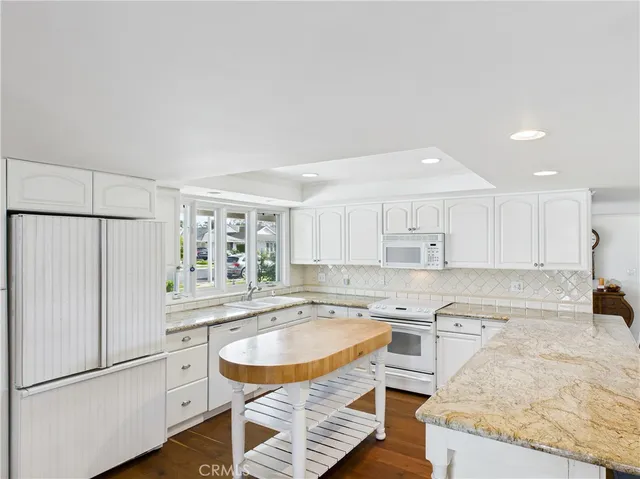 a large white kitchen with kitchen island a stove a sink and a counter top space