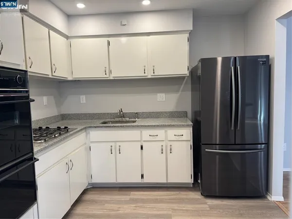 a kitchen with stainless steel appliances granite countertop a refrigerator stove and white cabinets