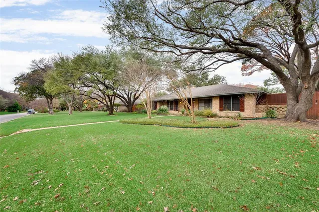 a view of house with a big yard and large trees