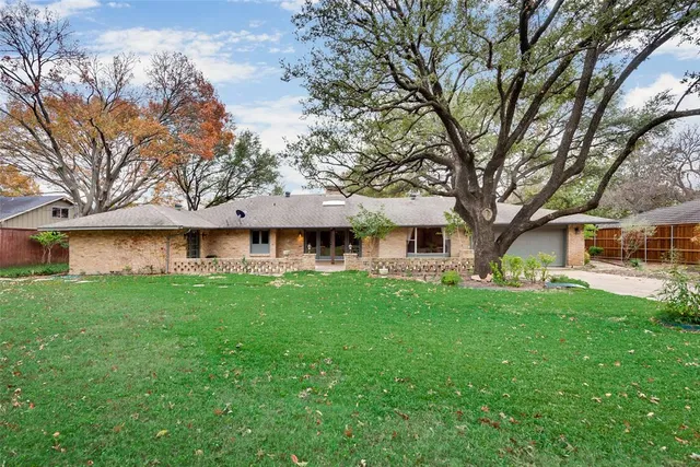 a front view of a house with a yard and trees