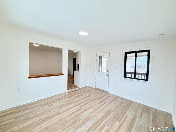 a view of an empty room with wooden floor and a window