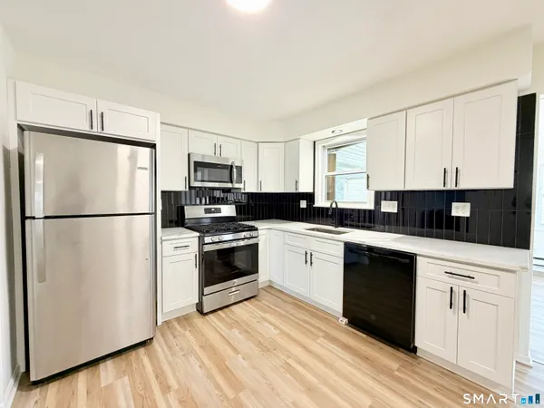 a kitchen with granite countertop a refrigerator stove a sink and dishwasher with wooden floor