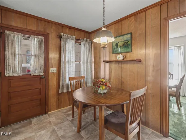 a kitchen with stainless steel appliances granite countertop a stove a refrigerator a sink a dining table and chairs