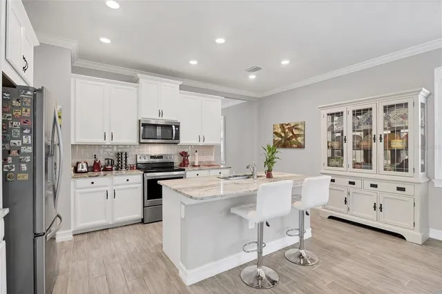 a kitchen that has a lot of cabinets a sink and wooden floor