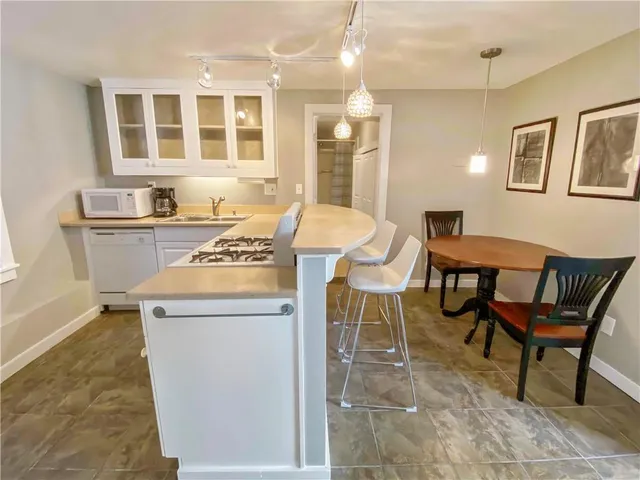 a open kitchen with a dining table chairs and a refrigerator