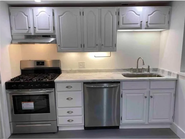 a kitchen with granite countertop white cabinets and stainless steel appliances